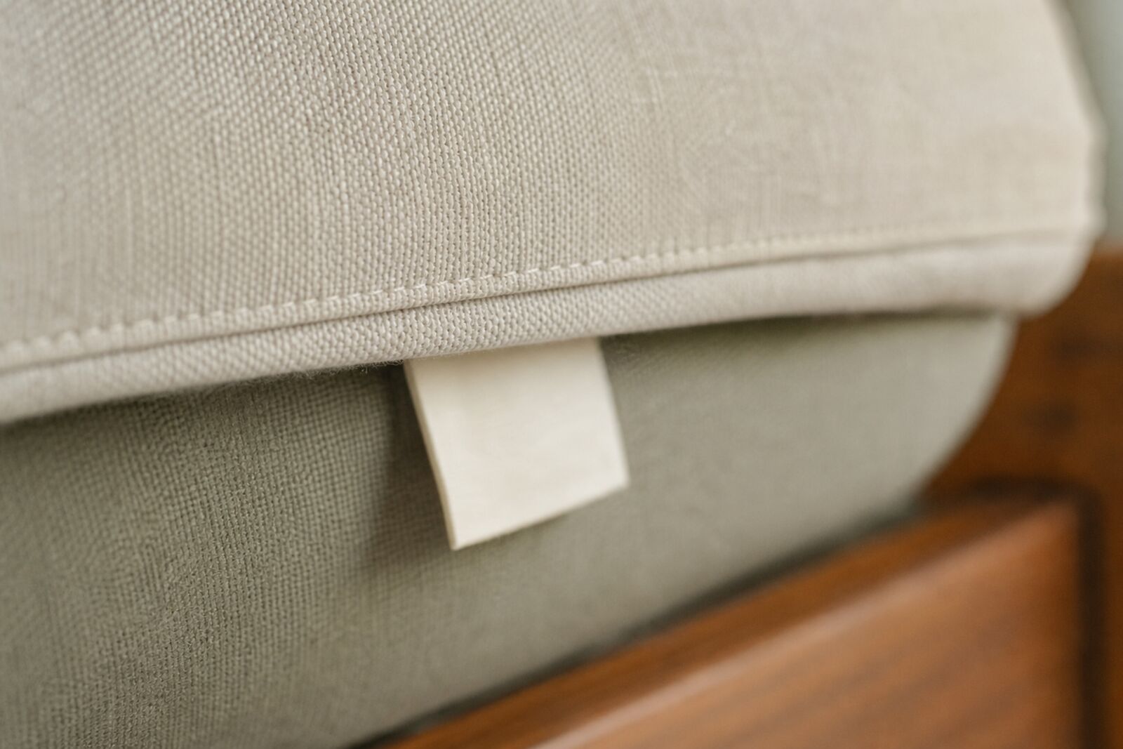 Close-up of a fabric care tag stitched under a sofa cushion, text out of focus