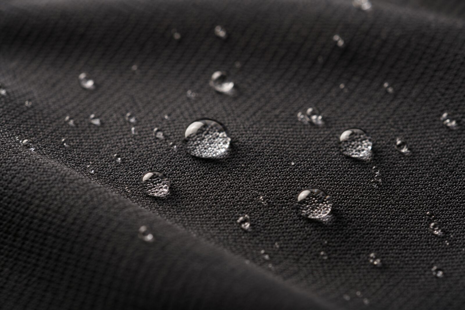 Water beading on a dark synthetic athletic fabric, macro shot