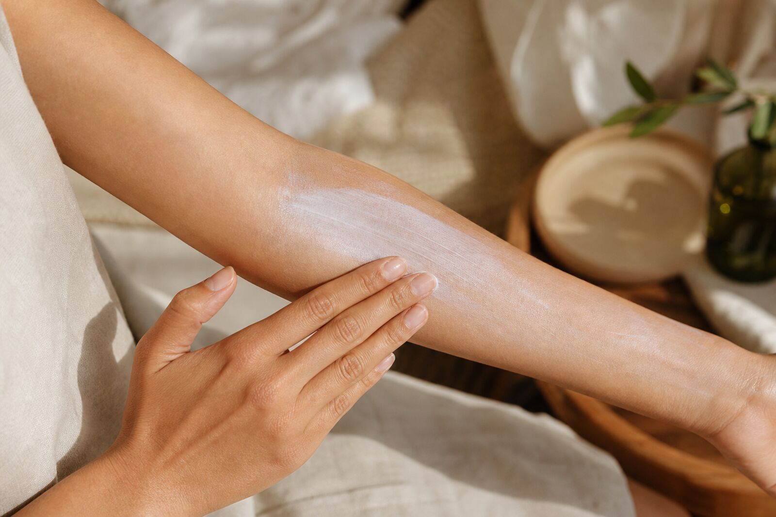 Hands applying mineral sunscreen to a forearm with a visible light white cast, close-up